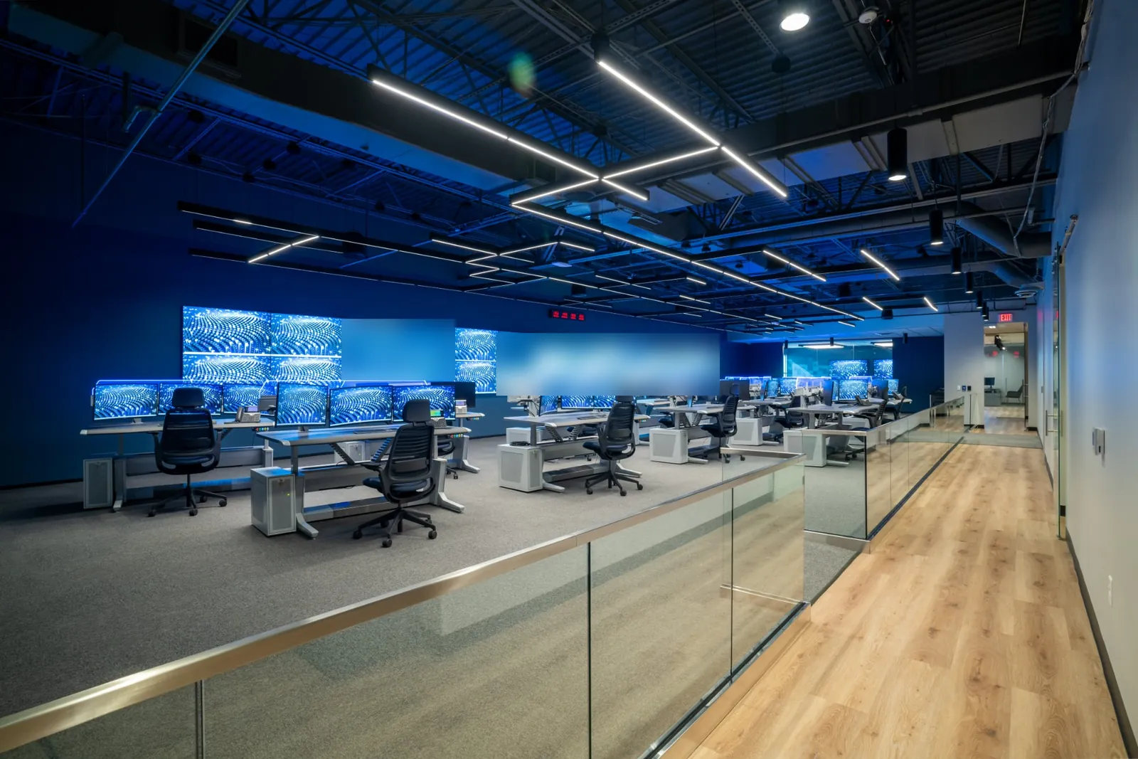 GSOC operations floor seen from the walkway, rows of operator consoles facing the video wall