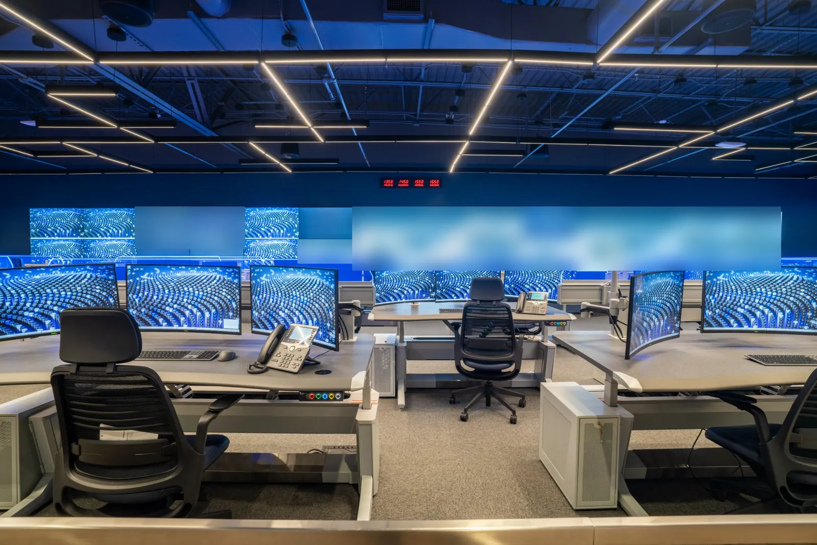 GSOC operator consoles with curved monitors in front of the video wall and time-zone clocks